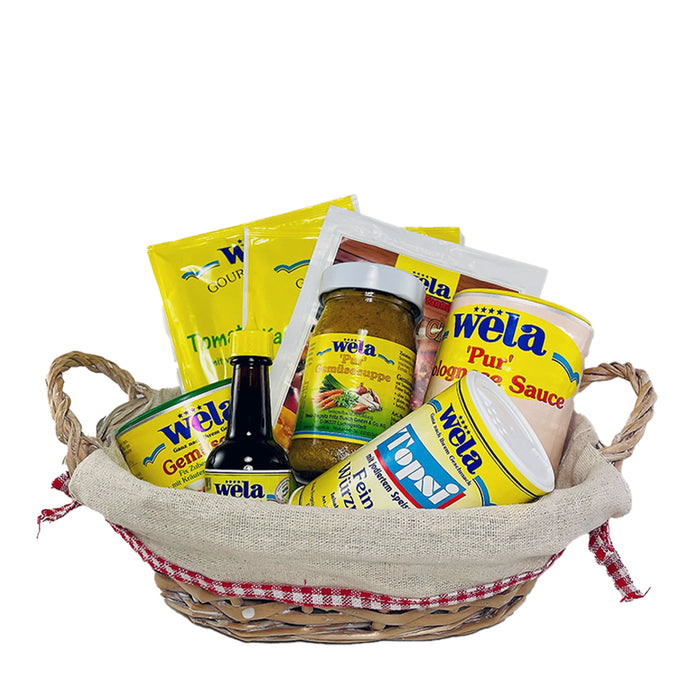 Wela Präsentkorb Vital mit verschiedenen Produkten – Glas, Beutel, Dosen und eine kleine Flasche im Weidenkorb.